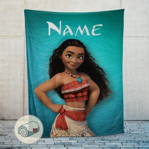 K&ouml;nnte beinhalten: T&uuml;rkisfarbene Decke mit einer Cartoonfigur mit langen schwarzen Haaren, die ein rotes Oberteil und einen beigen Rock tr&auml;gt. Das Wort "NAME" steht wei&szlig; oben. Die Figur l&auml;chelt.