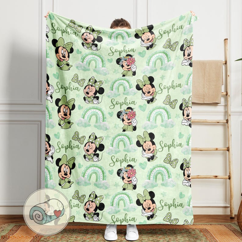 K&ouml;nnte beinhalten: Eine hellgr&uuml;ne Decke mit einem sich wiederholenden Muster aus Minnie Mouse, Regenbogen und Schmetterlingen. Der Name "Sophia" ist auf die Decke geschrieben. Die Decke besteht aus einem weichen Material, ideal f&uuml;r ein Kinderzimmer.
