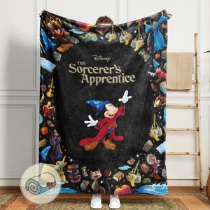 Pu&ograve; includere: Una morbida coperta con Topolino come apprendista stregone di Fantasia della Disney. Il design include il testo "The Sorcerer's Apprentice" e vari elementi magici su sfondo scuro. La coperta &egrave; arrotolata in un piccolo cerchio in basso.