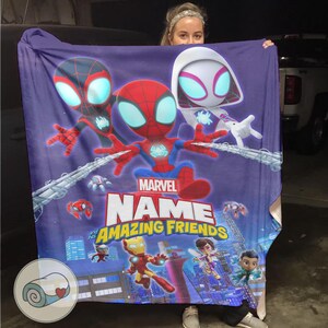 May include: A purple blanket featuring cartoon illustrations of Spider-Man, Miles Morales, and Spider-Gwen. The blanket has the text "Marvel Name and His Amazing Friends" and other characters in a cityscape.