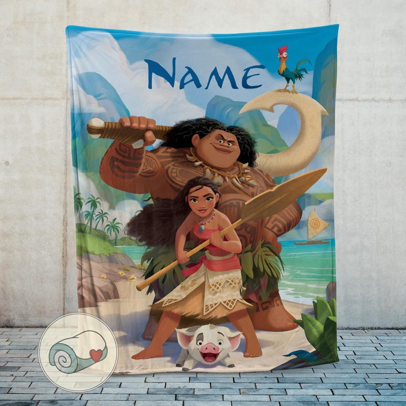 May include: A blue blanket featuring characters from the animated film Moana. The blanket displays the characters Moana, Maui, Pua, and Hei Hei, with the word "Name" at the top. The background shows a tropical beach scene with palm trees and ocean.