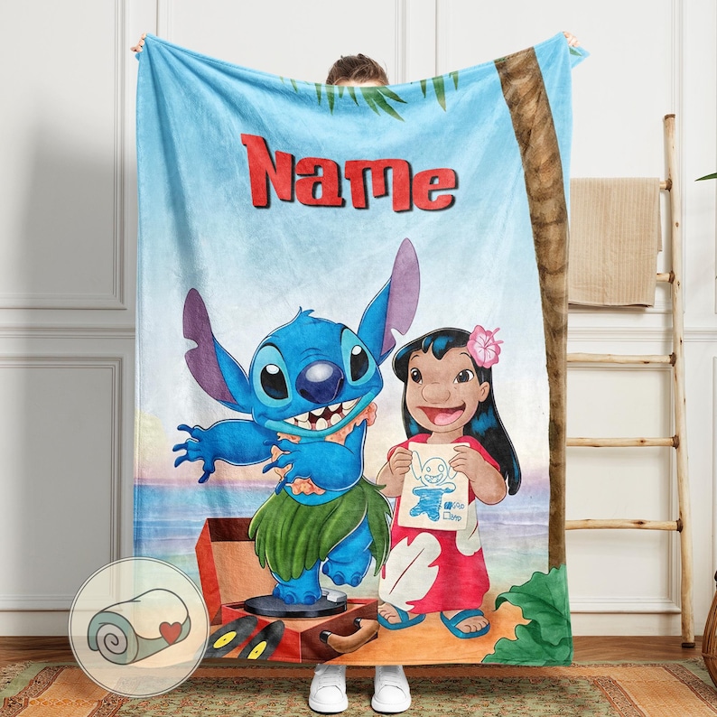 May include: A blue blanket featuring the characters Stitch and Lilo from the animated film. The blanket has a tropical beach scene background with the word "Name" in red letters. Stitch is wearing a grass skirt, and Lilo is holding a drawing.