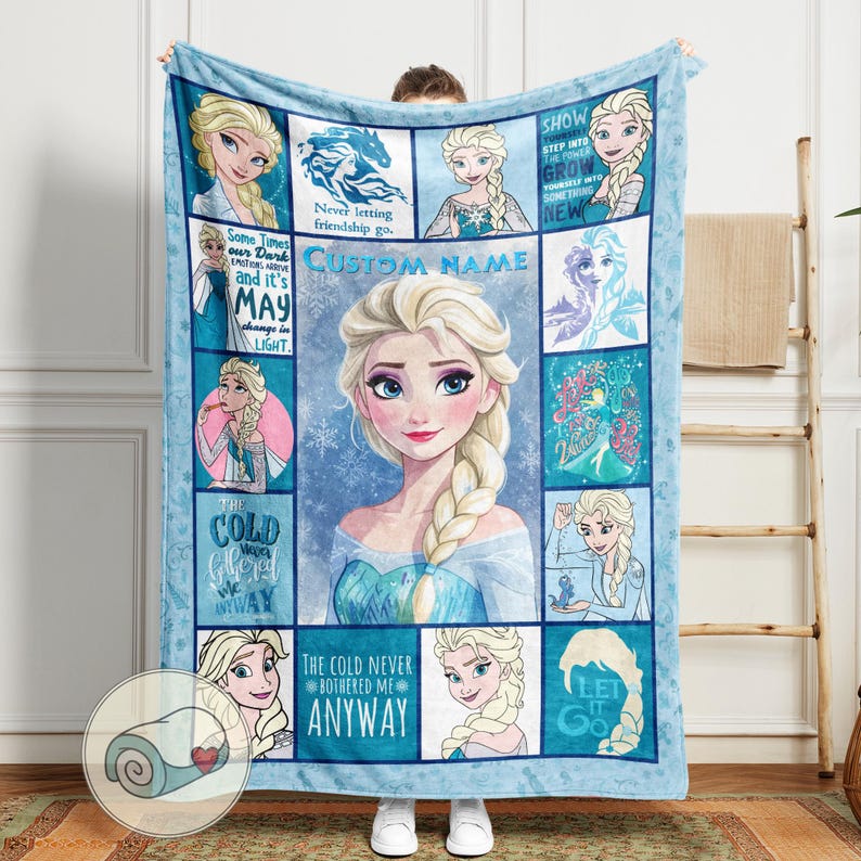 May include: A light blue fleece blanket featuring Elsa from Frozen. The blanket has a central portrait of Elsa, surrounded by smaller images and text including "CUSTOM NAME", "The Cold Never Bothered Me Anyway", and "Let It Go".