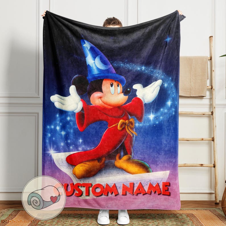 Pu&ograve; includere: Una morbida coperta con Topolino nei panni di un mago, con un cappello blu e una veste rossa, su uno sfondo stellato, viola e blu. La coperta ha la scritta "CUSTOM NAME" in rosso. Una coperta arrotolata con un cuore &egrave; nell'angolo.