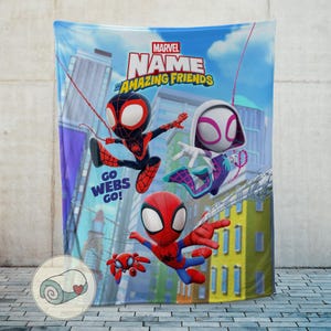 May include: A Marvel "Amazing Friends" blanket featuring cartoon Spider-Man characters in action poses against a city backdrop. The blanket has the text "Go Webs Go!" and a Marvel logo.