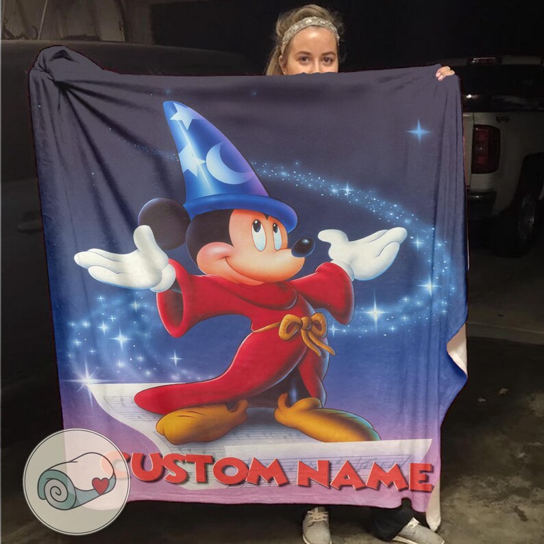 Pu&ograve; includere: Una grande coperta blu navy con una vivace illustrazione di Topolino vestito da mago. Mickey indossa un cappello blu con una luna crescente e stelle, una veste rossa e scarpe gialle. Il testo "CUSTOM NAME" &egrave; visibile in basso.