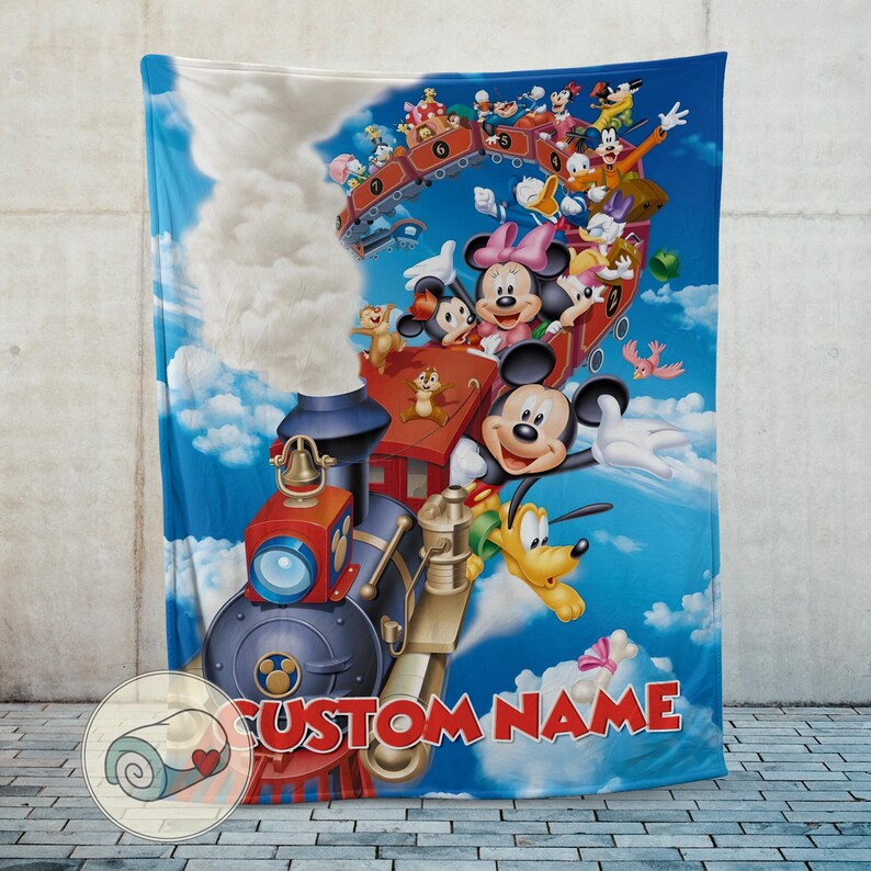 May include: A blue blanket featuring a train with Mickey Mouse, Minnie Mouse, Donald Duck, and other cartoon characters. The blanket has a custom name in red letters and a sky background with clouds.