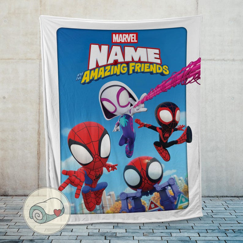 May include: A Marvel-themed blanket featuring the words "NAME and his AMAZING FRIENDS" above cartoon illustrations of Spider-Man characters. The blanket has a blue background with a white border and is displayed against a textured wall.