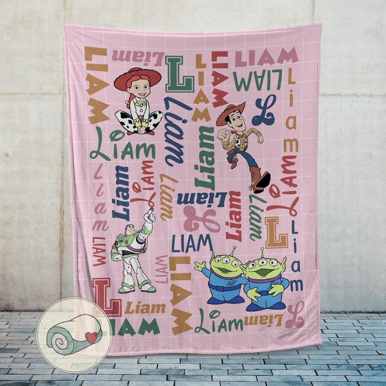 May include: Pink fleece blanket featuring Toy Story characters Jessie, Woody, Buzz Lightyear, and the Little Green Men. The name "Liam" is printed in various fonts and colors across the blanket. A rolled-up blanket with a heart is in the corner.