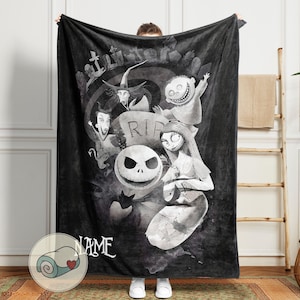 May include: Black and white fleece blanket featuring characters from The Nightmare Before Christmas. The design includes Jack Skellington, Sally, and other characters in a spooky graveyard scene. The word "NAME" is printed on the bottom.