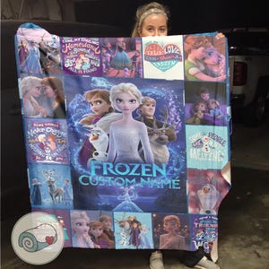 Puede incluir: Una manta grande y rectangular con tem&aacute;tica de Frozen con Elsa, Anna, Olaf y Kristoff. La manta tiene un fondo azul con varias im&aacute;genes y texto, incluyendo "Frozen Custom Name", "Some Things Never Change" y "True Love".