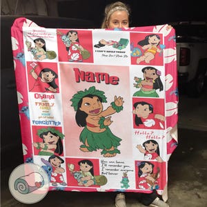 May include: A pink and white blanket featuring cartoon images of a character in various poses. The blanket has the word "Name" in the center, and the phrase "Ohana means family" is also visible. The blanket is made of a soft material.