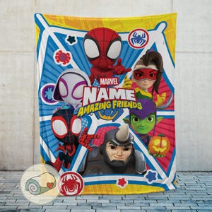 May include: A colorful Marvel Amazing Friends blanket featuring Spider-Man and other characters. The blanket has a blue, yellow, and white geometric background with the Marvel logo and the text "NAME" and "AMAZING FRIENDS".