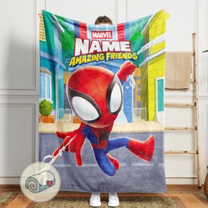 May include: A Marvel Spider-Man blanket featuring a cartoon illustration of Spider-Man in a dynamic pose. The blanket has a cityscape background and the text "Marvel Name and his Amazing Friends". The blanket is primarily red, blue, and yellow.