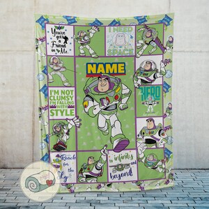 May include: A green blanket featuring Buzz Lightyear from Toy Story. The blanket has a grid pattern with various images of Buzz, along with phrases like "You've got a Friend in Me" and "Reach for the Sky". The word "NAME" is also displayed.