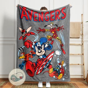 May include: A gray blanket featuring a cartoon illustration of Avengers characters, including Mickey Mouse as Captain America, Iron Man, and Thor. The word "AVENGERS" is printed in red and blue at the top. The blanket is made of a soft material.