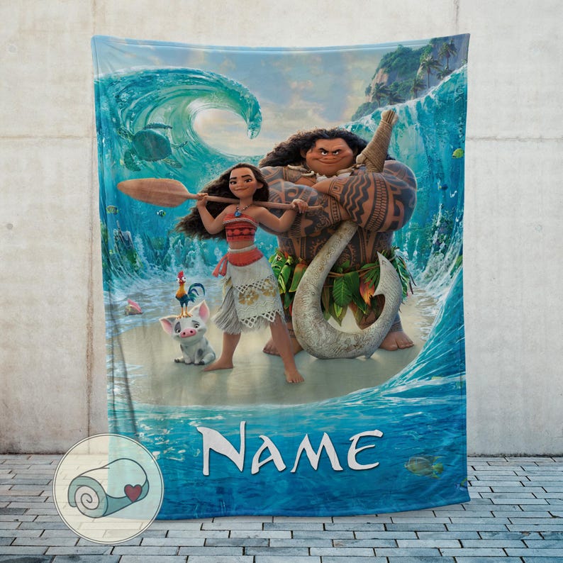 May include: A blue blanket featuring characters from the animated film Moana. The design includes Moana, Maui, Pua the pig, and Hei Hei the rooster, set against a backdrop of ocean waves and a tropical island. The word "Name" is printed on the blanket.
