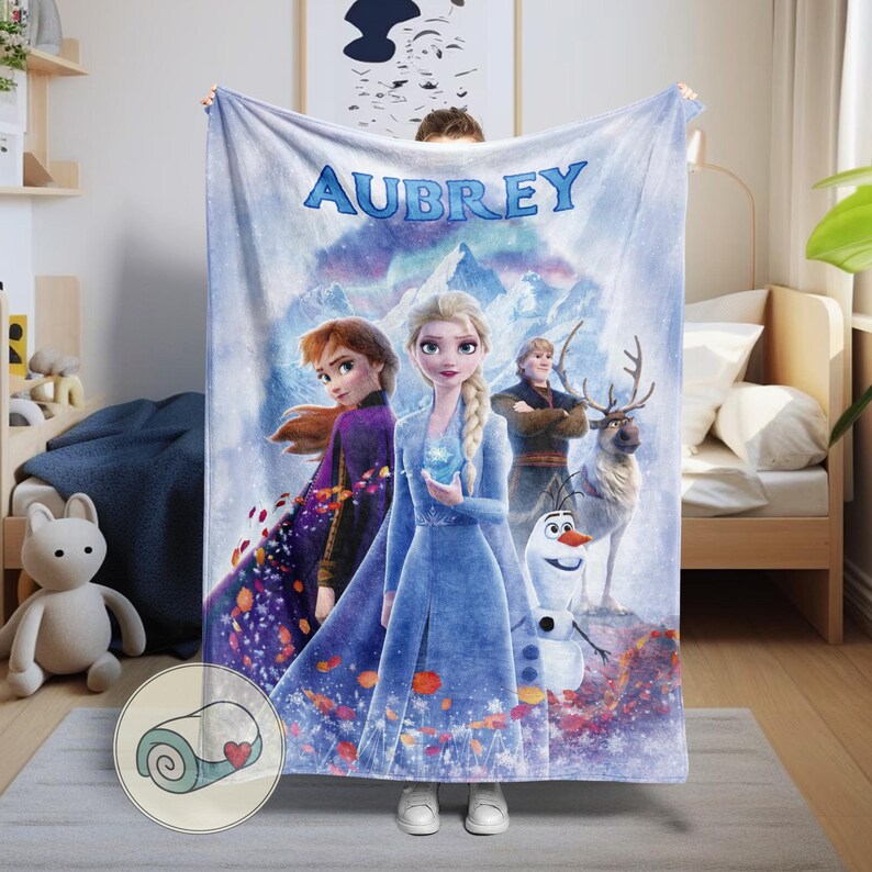 May include: A personalized blanket featuring characters from the animated film "Frozen." The blanket displays the name "AUBREY" in blue script across the top. The design includes Elsa, Anna, Kristoff, Olaf, and Sven against a snowy mountain backdrop.