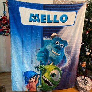 Pu&ograve; includere: Una grande coperta rettangolare blu e bianca con personaggi del film d'animazione "Monsters & Co.". La coperta presenta la scritta "MELLO" in grandi lettere blu. Sono presenti anche i personaggi Sulley, Mike Wazowski e Boo.