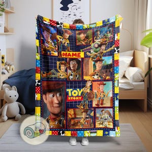 May include: A plush blanket featuring a collage of images from the animated film "Toy Story." The design includes images of Woody, Buzz Lightyear, and other characters. The blanket has a blue grid background with a colorful patchwork border.