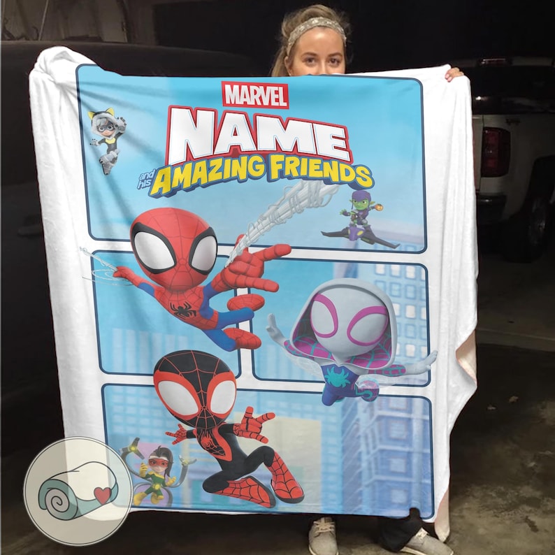 May include: A Marvel "Amazing Friends" blanket featuring Spider-Man, Spider-Gwen, and Miles Morales. The blanket has a light blue background with comic book style panels and character illustrations. The Marvel logo and "Name" text are displayed at the top.