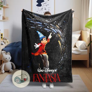 Peut inclure: Couverture en polaire noire avec Mickey Mouse en sorcier, pointant vers un ciel &eacute;toil&eacute;. Le texte "Walt Disney's Fantasia" est en rouge. Une illustration de couverture roul&eacute;e est dans le coin.