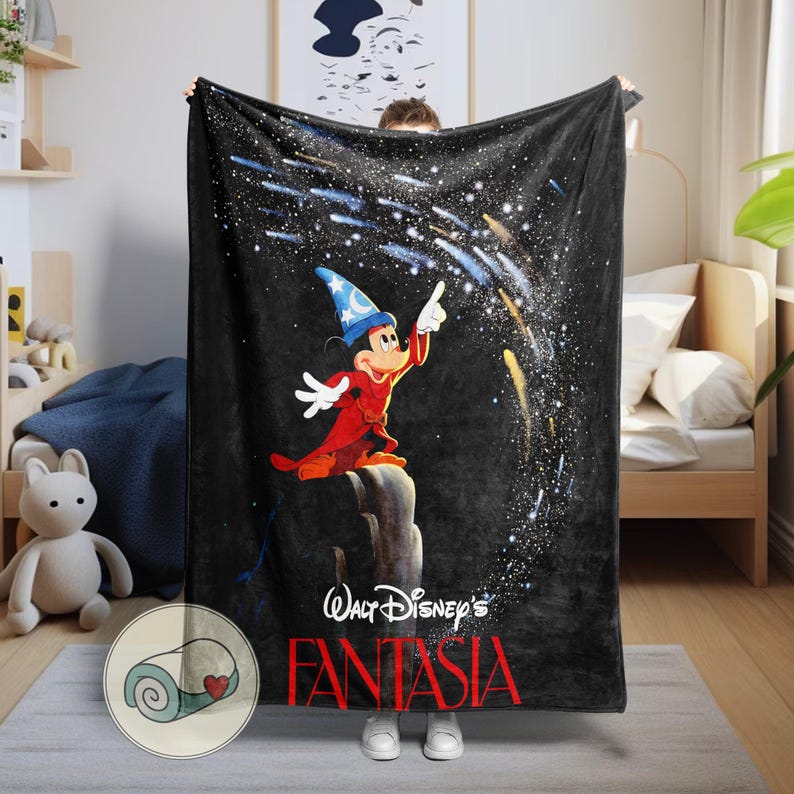 Peut inclure: Couverture en polaire noire avec Mickey Mouse en sorcier, pointant vers un ciel &eacute;toil&eacute;. Le texte "Walt Disney's Fantasia" est en rouge. Une illustration de couverture roul&eacute;e est dans le coin.