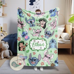 Puede incluir: Una manta verde con personajes de dibujos animados y dise&ntilde;os florales. La manta tiene un patr&oacute;n de cuadr&iacute;cula y una etiqueta central con el nombre "Ethan". La manta est&aacute; enrollada en un peque&ntilde;o c&iacute;rculo en la esquina inferior izquierda.