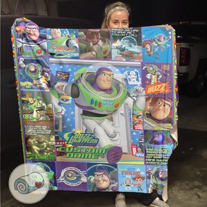 Pu&ograve; includere: Una coperta colorata con Buzz Lightyear di Toy Story. Il design include varie immagini di Buzz, testo e una sezione nome personalizzabile. La coperta &egrave; prevalentemente verde, viola e bianca.