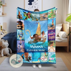 Może przedstawiać: Niebieski polarowy koc z scenami i postaciami z filmu Disneya "Moana". Koc ma centralny obraz Moany na łodzi, otoczony mniejszymi panelami z postaciami i cytatami. Widoczny jest tekst "Moana" i "Custom Name".