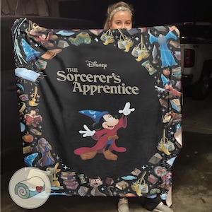 Pu&ograve; includere: Una coperta nera con Topolino in abito da mago da "L'apprendista stregone" di Disney. La coperta ha un bordo di oggetti e personaggi magici del film, con il testo del titolo ben visibile.