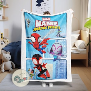 May include: A white Marvel "Amazing Friends" blanket featuring Spider-Man, Spider-Gwen, and Miles Morales. The blanket has a blue background with comic book style panels and the Marvel logo. The blanket is made of a soft material.