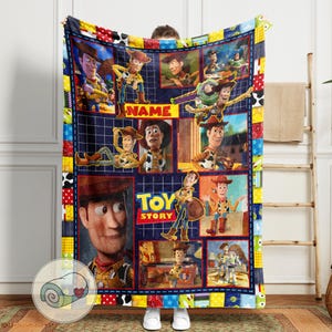 May include: A plush, rectangular blanket featuring a collage of images from the animated film "Toy Story." The design includes various character portraits and the film's logo. The blanket has a patchwork border with a blue grid background and the word "NAME" in yellow.