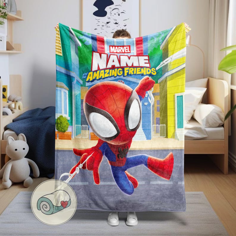 May include: A Marvel "Amazing Friends" blanket featuring a cartoon Spider-Man in a dynamic pose. The blanket has a cityscape backdrop and the Marvel logo. The blanket is red, blue, and white.