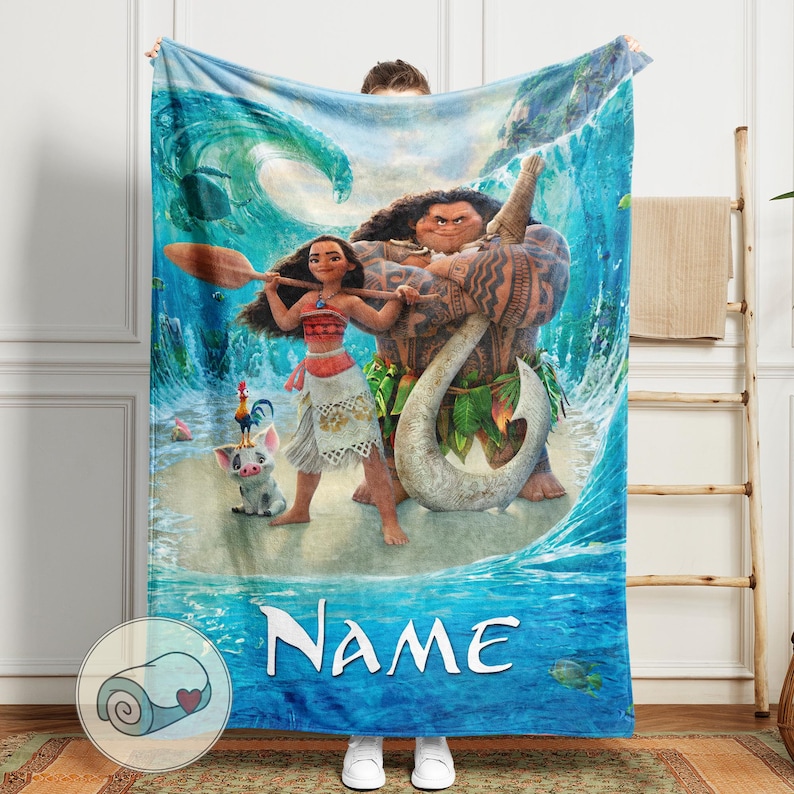 May include: A blue blanket featuring characters from the animated movie Moana. The blanket depicts Moana, Maui, Pua, and Hei Hei in a tropical ocean scene. The word "Name" is printed in white at the bottom. The blanket is made of soft material.