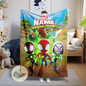 Pode incluir: Um cobertor Marvel "Amazing Friends" com personagens de desenho animado do Homem-Aranha. O cobertor tem um fundo de c&eacute;u azul com &aacute;rvores verdes e uma ponte. Os personagens usam fantasias vermelhas, pretas e brancas. O cobertor &eacute; enrolado em um pequeno c&iacute;rculo.