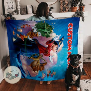 May include: A blue blanket featuring a colorful illustration of Mickey Mouse in a wizard hat, Donald Duck, and other cartoon characters. The blanket has the text "CUSTOM NAME" in red. A rolled-up blanket with a heart is in the corner.