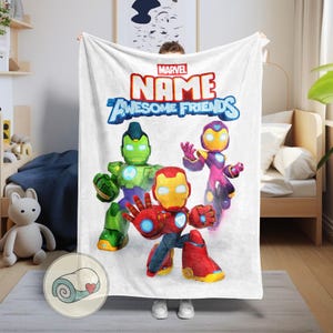 Op de afbeelding: Witte Marvel-deken met de tekst "NAME AWESOME FRIENDS" en cartoonillustraties van Iron Man, Hulk en een ander personage. Een opgerold beeld staat in de hoek.