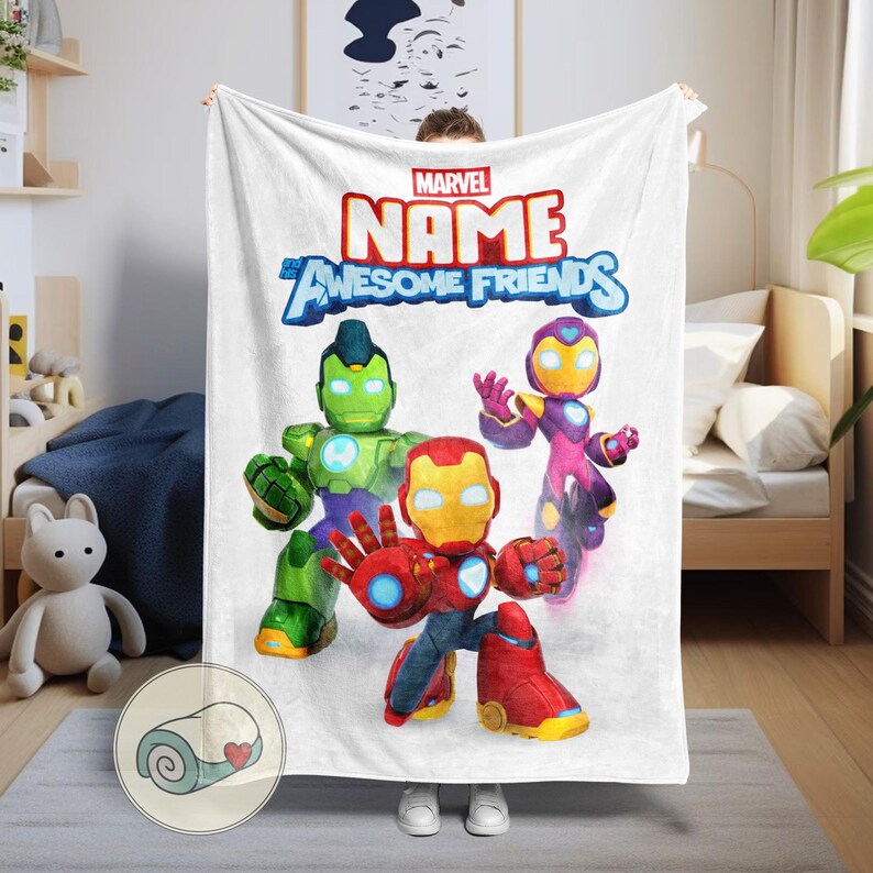 Op de afbeelding: Witte Marvel-deken met de tekst "NAME AWESOME FRIENDS" en cartoonillustraties van Iron Man, Hulk en een ander personage. Een opgerold beeld staat in de hoek.