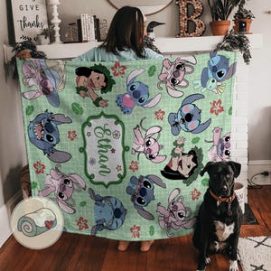 Puede incluir: Una manta verde claro con personajes de dibujos animados en varias poses. La manta tiene un patr&oacute;n repetido de personajes de Stitch y Lilo, con un nombre en un marco decorativo. Una manta enrollada con un coraz&oacute;n est&aacute; en la esquina.