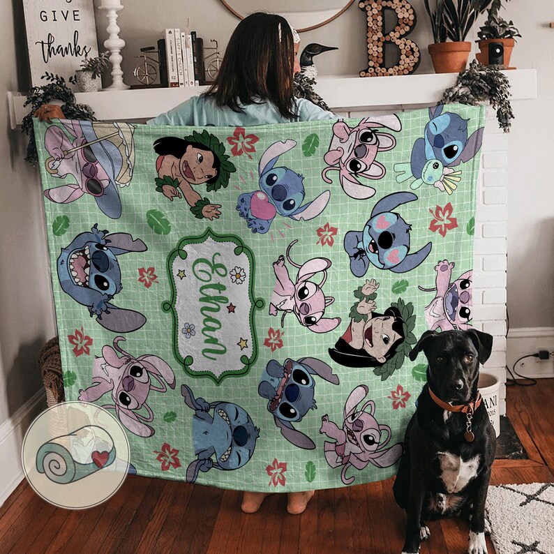 Puede incluir: Una manta verde claro con personajes de dibujos animados en varias poses. La manta tiene un patr&oacute;n repetido de personajes de Stitch y Lilo, con un nombre en un marco decorativo. Una manta enrollada con un coraz&oacute;n est&aacute; en la esquina.