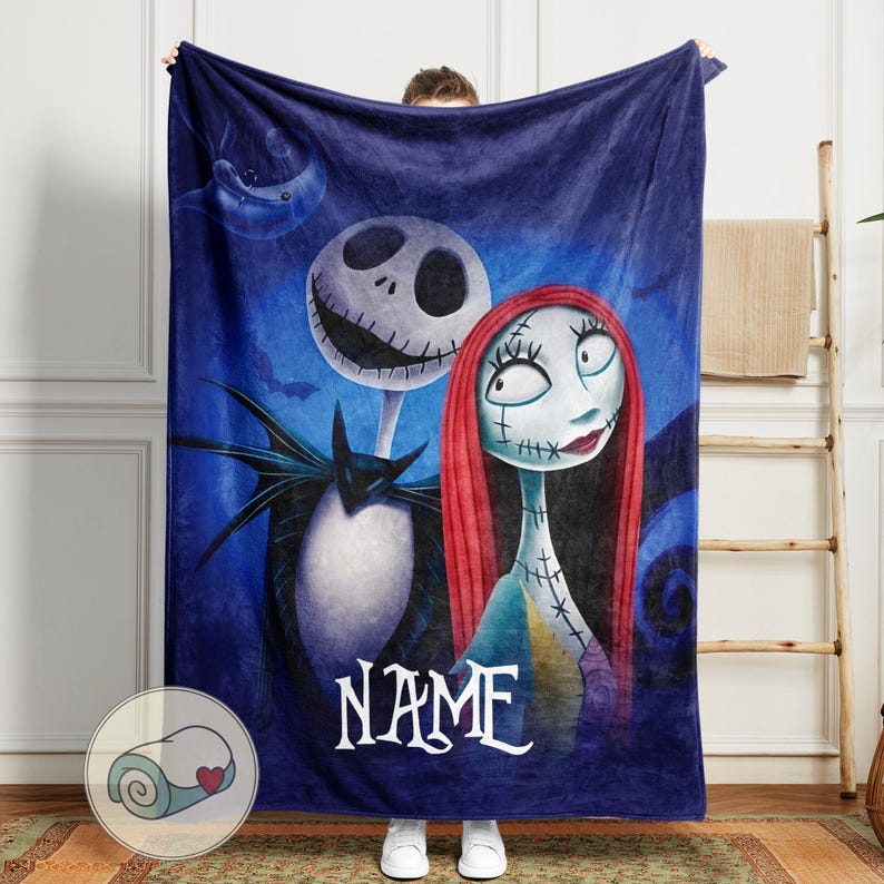 May include: A navy blue fleece blanket featuring Jack Skellington and Sally from The Nightmare Before Christmas. The blanket has a blue background with a crescent moon and the word "NAME" in white script.