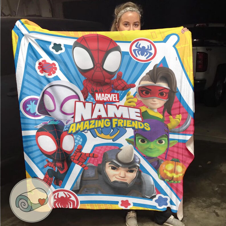 May include: A colorful Marvel "Amazing Friends" blanket featuring Spider-Man, Spider-Gwen, and other characters. The blanket has a blue, yellow, and white background with character illustrations and the Marvel logo. The blanket is rectangular.