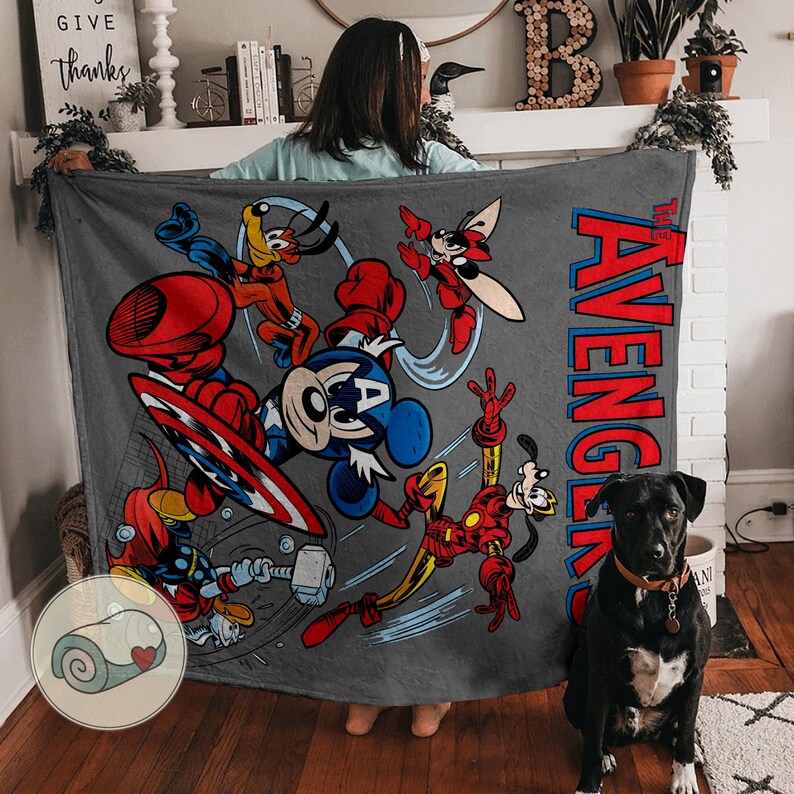 May include: A gray blanket featuring cartoon characters in action poses. The blanket has the text "The Avengers" in red and blue. The characters include Mickey Mouse as Captain America, Goofy as Iron Man, and Donald Duck as Thor.