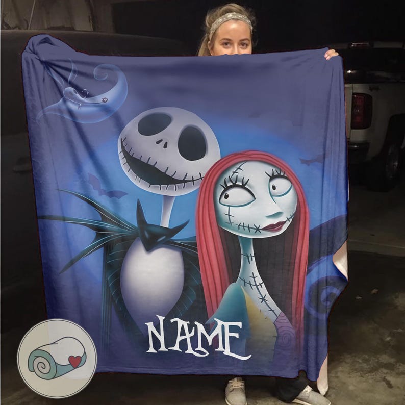 May include: A dark blue blanket featuring Jack Skellington and Sally from The Nightmare Before Christmas, with a crescent moon and bats in the background. The blanket has the word "NAME" in white script. A small logo of a rolled blanket is in the lower left corner.
