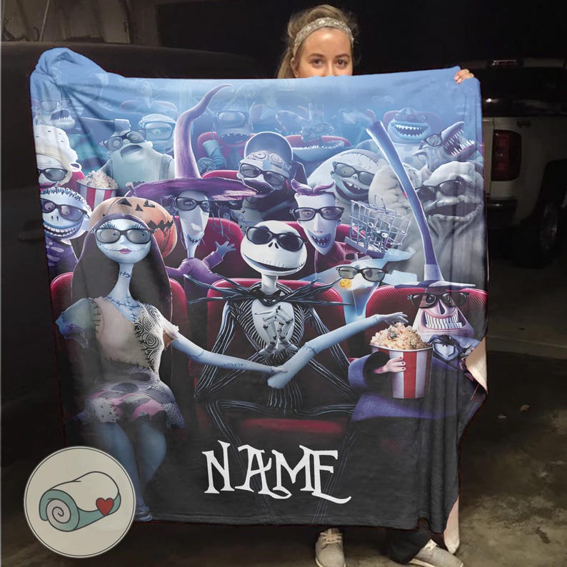Puede incluir: Una manta azul con una escena de pel&iacute;cula con personajes de The Nightmare Before Christmas. La manta muestra a Jack Skellington y Sally en un cine, rodeados de otros personajes. La palabra "NAME" est&aacute; impresa en la manta.