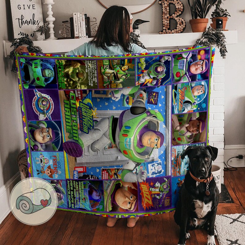 Pu&ograve; includere: Una coperta colorata con Buzz Lightyear di Toy Story. Il design include varie immagini del personaggio, le parole "Buzz Lightyear" e "Custom Name". La coperta &egrave; principalmente blu, verde e viola.
