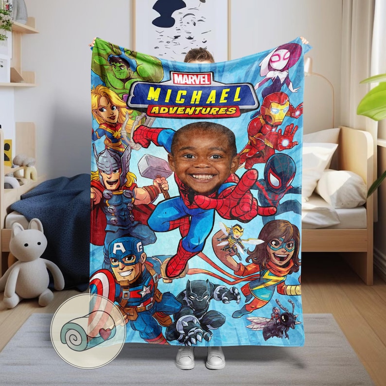 K&ouml;nnte beinhalten: Eine blaue Marvel Adventures-Decke mit dem l&auml;chelnden Gesicht eines Kindes als zentrales Bild, umgeben von verschiedenen Marvel-Superhelden. Die Decke enth&auml;lt das Marvel-Logo und den Namen "MICHAEL". Die Decke ist in einem kreisf&ouml;rmigen Bild aufgerollt.