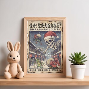 May include: A framed print with Japanese text and illustrations. The artwork depicts a skeleton wearing a Santa hat, surrounded by various monsters in a snowy street scene. A plush bunny and a potted succulent are on the shelf.