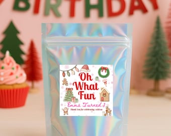 May include: A holographic zip-lock bag with a square label that reads "Oh What Fun" with Christmas-themed illustrations. The background features a "Happy Birthday" banner, a red balloon, and a cupcake.